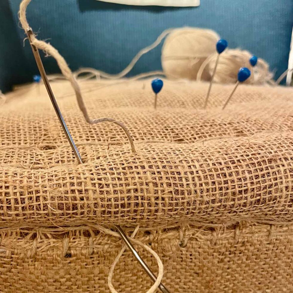 Nærbilde av historisk stolsete i stoff med stoppenåler i